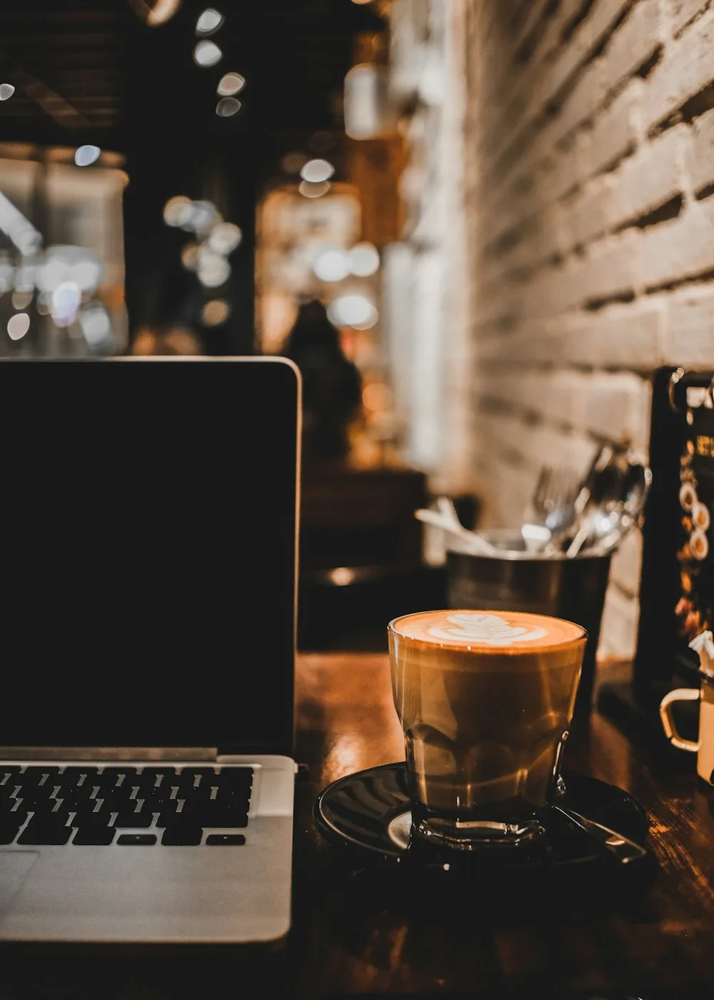 Pemilik usaha kecil memakai laptop sambil sipping di kedai